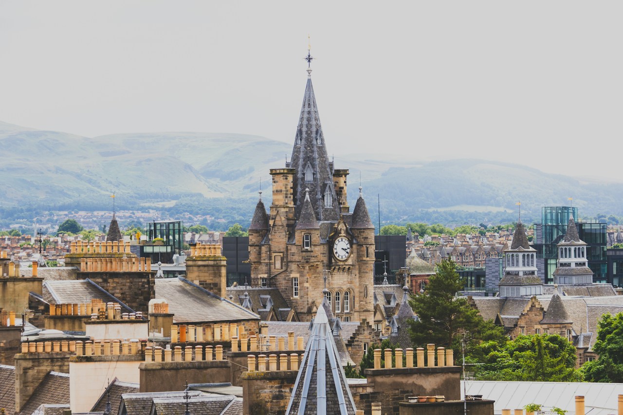 Historic stone clock tower overlooking a dense city of traditional buildings.